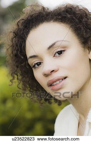 Stock Image - "Portrait of young woman smiling, outdoors". Fotosearch