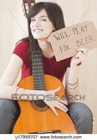 Stock Photo - "Portrait of young woman with guitar, playing for beer". Fotosearch