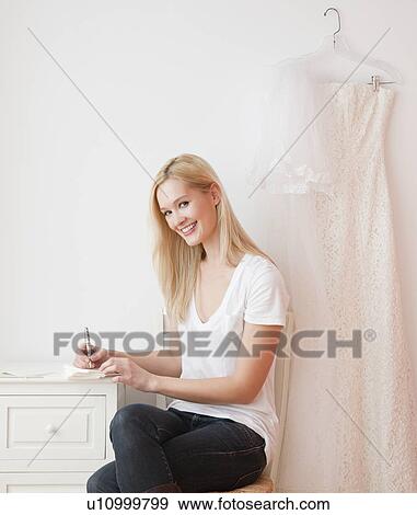 Stock Photo - Portrait of young woman writing wedding invitation. Fotosearch