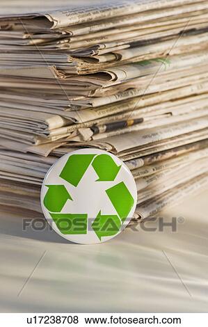 Stock Photo - "Recycling sign by pile of newspapers, studio shot". Fotosearch