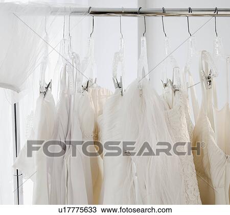Stock Image - Row of wedding dresses hanging on clothes rail. Fotosearch