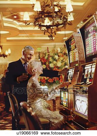 Stock Photo - "Senior couple in casino playing on slot machines, Las Vegas, Nevada, USA". Fotosearch