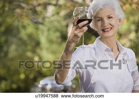 "Senior woman holding glass of red wine, portrait" View Large Photo Image Stock Photo - "Senior woman holding glass of red wine, portrait". Fotosearch
