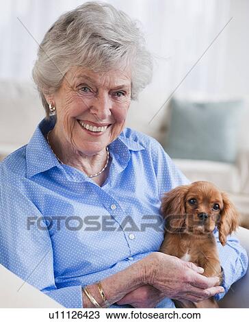 Stock Image - Senior woman hugging puppy. Fotosearch