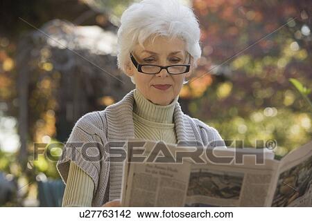 Senior woman reading newspaper outdoors View Large Photo Image Stock Image - Senior woman reading newspaper outdoors. Fotosearch
