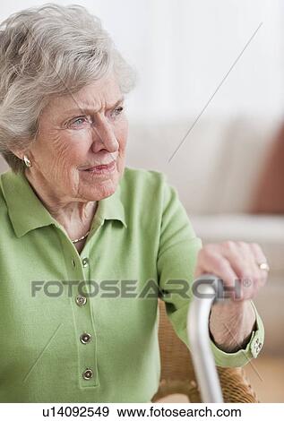 Senior woman sitting and holding walking stick View Large Photo Image Stock Photo - Senior woman sitting and holding walking stick. Fotosearch
