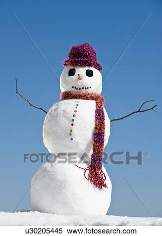 Stock Photography - "Snowman wearing hat and scarf, clear sky in background". Fotosearch