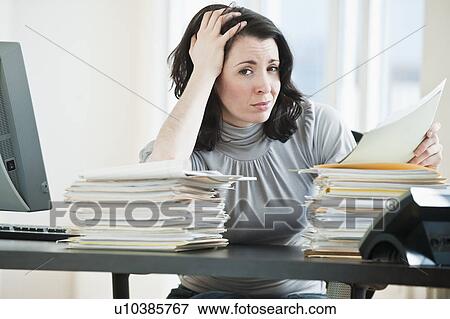Stressed business woman holding paperwork in office View Large Photo Image Stock Photo - Stressed business woman holding paperwork in office. Fotosearch