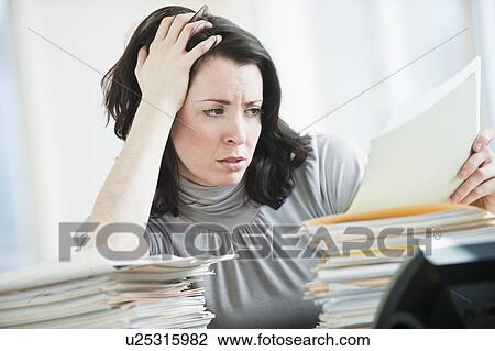 Stressed business woman reading paperwork in office View Large Photo Image Stock Image - Stressed business woman reading paperwork in office. Fotosearch