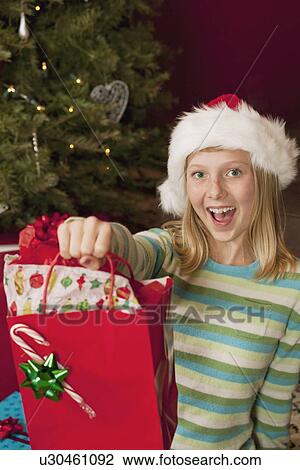 Teenage girl (13-15) wearing Santa hat holding Christmas gift View Large Photo Image Stock Image - Teenage girl (13-15) wearing Santa hat holding Christmas gift. Fotosearch