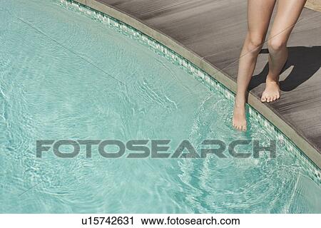 Stock Image - Teenage girl entering swimming pool. Fotosearch