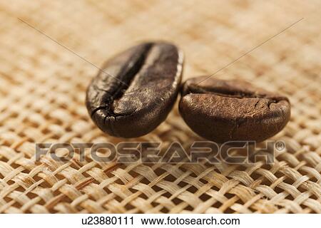 Stock Image - "Two roast coffee beans on fabric, studio shot". Fotosearch