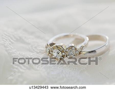 Stock Image - Two wedding rings on bed. Fotosearch