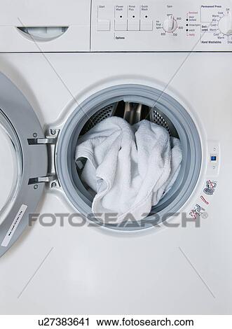 Stock Image - "Washing machine with laundry sticking out, close-up". Fotosearch