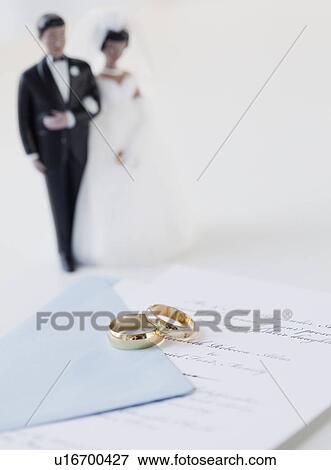 Wedding rings by bride and groom cake toppers on marriage certificate View Large Photo Image Stock Photo - Wedding rings by bride and groom cake toppers on marriage certificate. Fotosearch