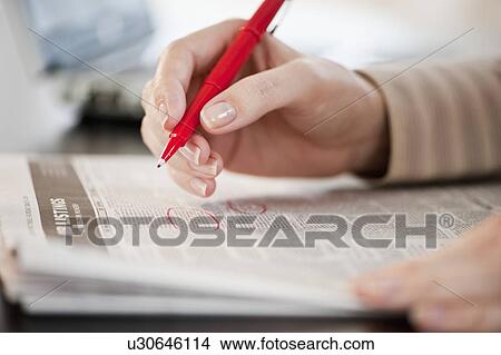 Picture - "Woman circling classfields, close-up". Fotosearch