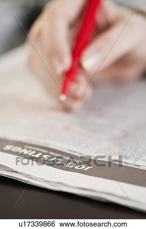 Stock Photograph - "Woman circling classfields, close-up". Fotosearch