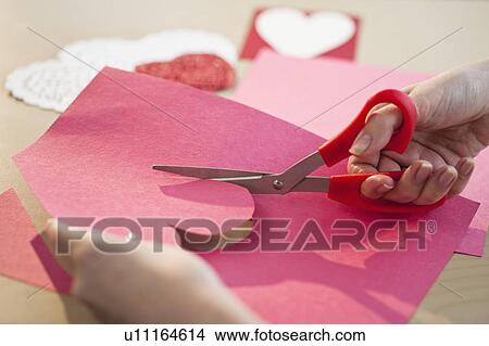 "Woman cutting out heart in paper, close-up" View Large Photo Image Picture - "Woman cutting out heart in paper, close-up". Fotosearch