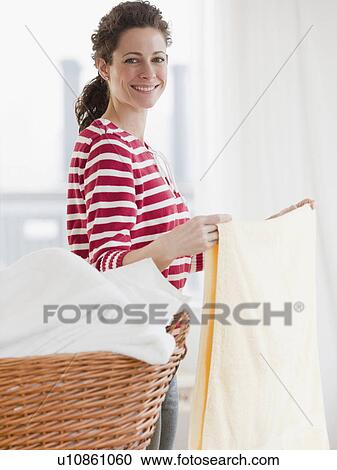 Stock Image - "Woman holding laundry, smiling, portrait". Fotosearch