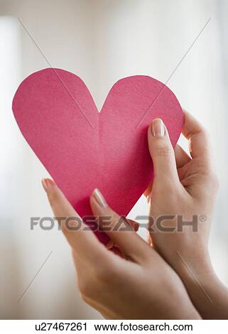 Stock Image - "Woman holding paper heart, close-up". Fotosearch