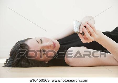 "Woman lying on floor using pda, studio shot" View Large Photo Image Stock Image - "Woman lying on floor using pda, studio shot". Fotosearch