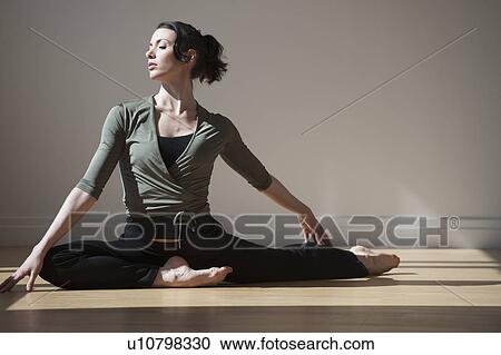 Stock Image - "Woman performing stretching exercise, studio shot". Fotosearch