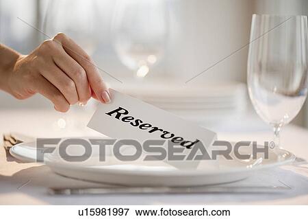 Stock Photo - "Woman placing tag on restaurant table, close-up". Fotosearch