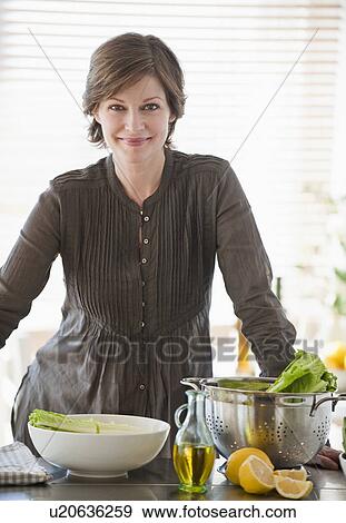 "Woman preparing food in kitchen, portrait" View Large Photo Image Stock Photo - "Woman preparing food in kitchen, portrait". Fotosearch