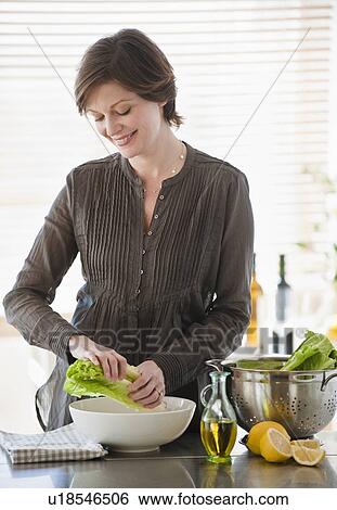 Stock Photograph - Woman preparing food in kitchen. Fotosearch