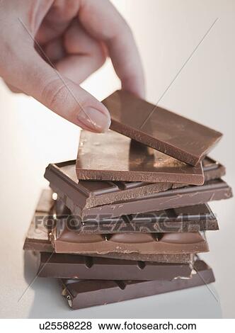 Stock Photo - "Woman removing bar of chocolate from stack, close-up". Fotosearch