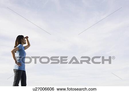 Woman shielding eyes against sky View Large Photo Image Stock Photograph - Woman shielding eyes against sky. Fotosearch