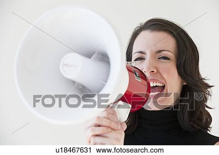 Stock Image - "Woman shouting through megaphone, studio shot". Fotosearch