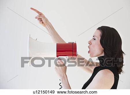 Stock Photo - "Woman shouting through megaphone, studio shot". Fotosearch