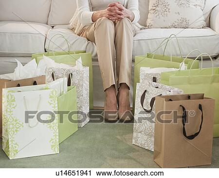 Woman sitting on sofa with shopping bags View Large Photo Image Stock Image - Woman sitting on sofa with shopping bags. Fotosearch