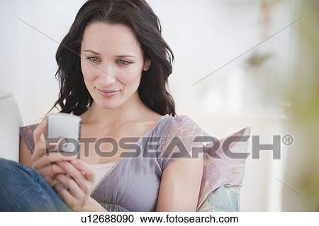 Stock Image - "Woman text messaging, smiling". Fotosearch