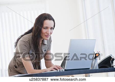 Stock Photo - "Woman using computer in office, smiling". Fotosearch
