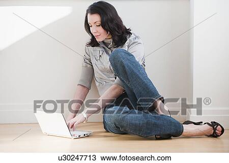 Stock Image - Woman using laptop on floor. Fotosearch