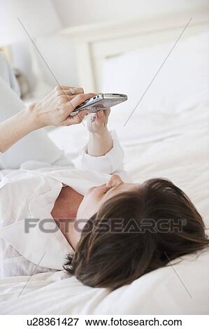 Stock Photo - Woman using pda on bed. Fotosearch