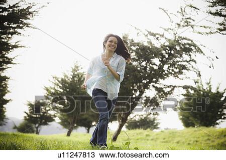 Stock Image - Woman walking in park. Fotosearch