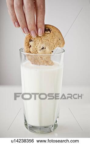 Woman's hand dipping cookie in glass of milk View Large Photo Image Stock Photograph - Woman's hand dipping cookie in glass of milk. Fotosearch