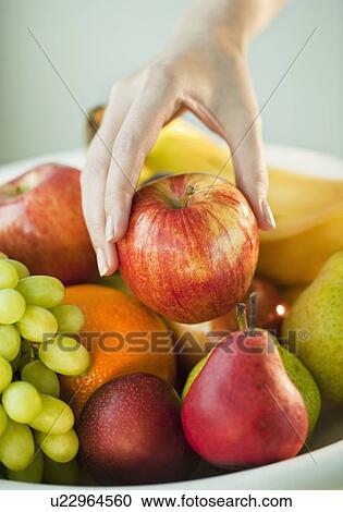 Stock Image - Woman's hand taking apple from fruit bowl. Fotosearch