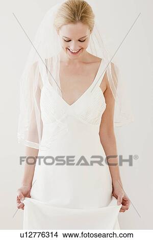 Young bride holding wedding dress and looking down View Large Photo Image Picture - Young bride holding wedding dress and looking down. Fotosearch