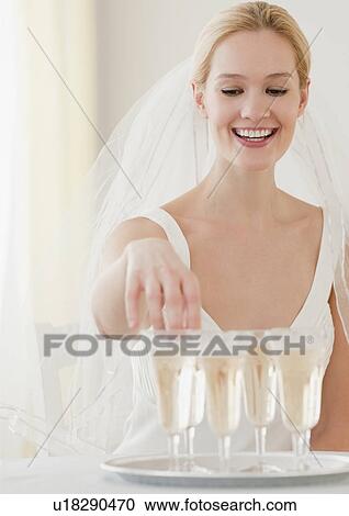 Stock Image - Young bride reaching for glass of champagne. Fotosearch