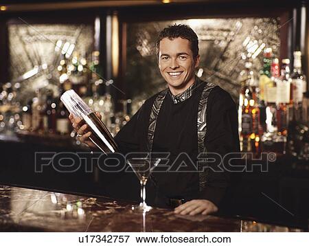 "Young man standing behind bar shaking cocktail shaker, portrait" View Large Photo Image Stock Photo - "Young man standing behind bar shaking cocktail shaker, portrait". Fotosearch