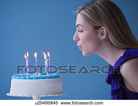 "Young woman blowing candles on birthday cake, studio shot" View Large Photo Image Stock Photography - "Young woman blowing candles on birthday cake, studio shot". Fotosearch