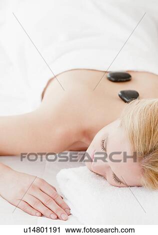 Stock Image - Young woman having hot stone therapy. Fotosearch