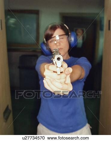 Stock Image - Young woman holding gun. Fotosearch