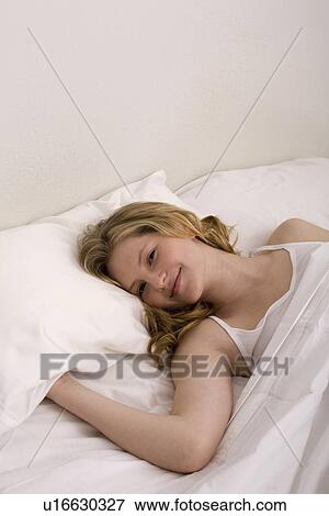 Stock Photo - Young woman laying in bed. Fotosearch