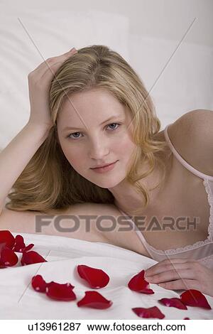 Young woman laying in bed with flower pedals View Large Photo Image Stock Photo - Young woman laying in bed with flower pedals. Fotosearch