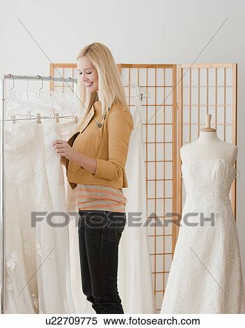 Young woman looking for wedding dress in bridal shop View Large Photo Image Stock Photography - Young woman looking for wedding dress in bridal shop. Fotosearch